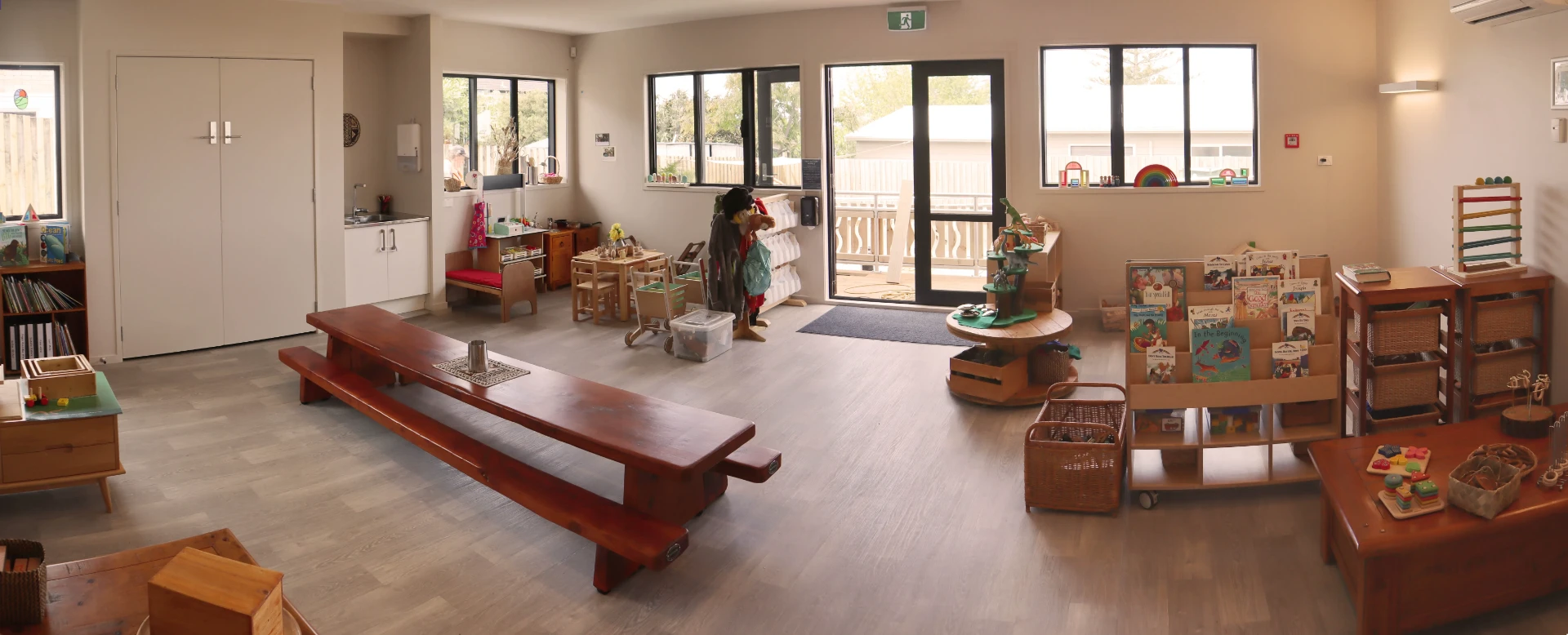 The Gecko Room for two year olds with a long wooden table, book shelves and home corner