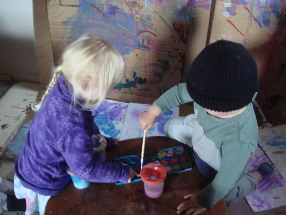 Two children painting side by side in the art area