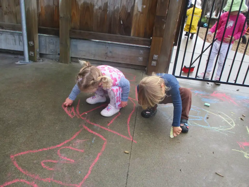 Two children drawing with chalk on the concrete outside