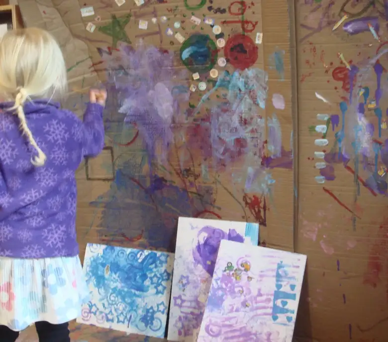 A child adding colour to a large collaborative cardboard art wall