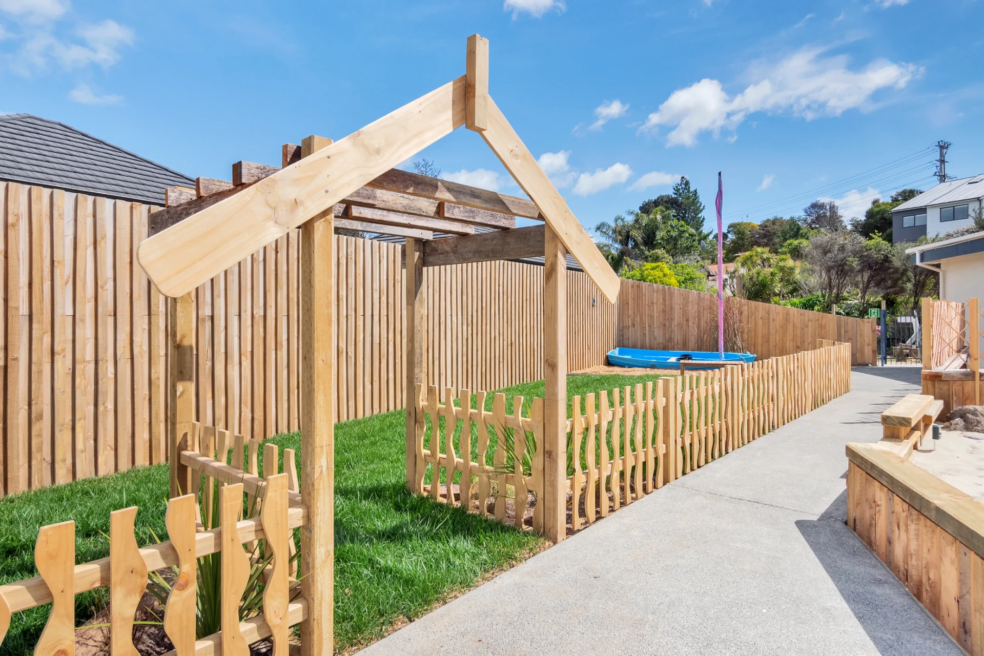 Timber archway leading onto the lawn and picket fenced play area