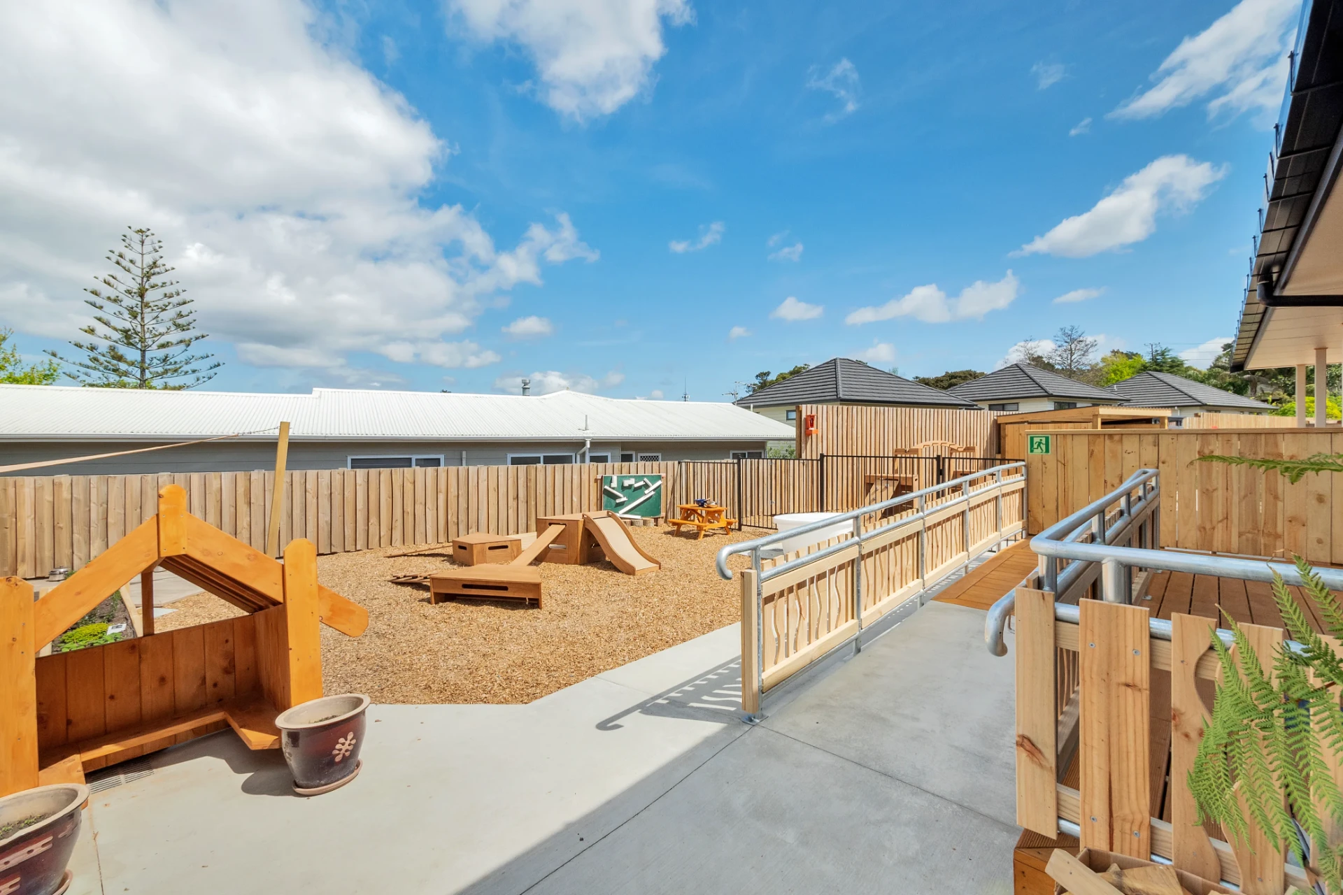 The Children's Ark outdoor playground in Torbay with wooden climbing blocks, garden beds and a fenced yard