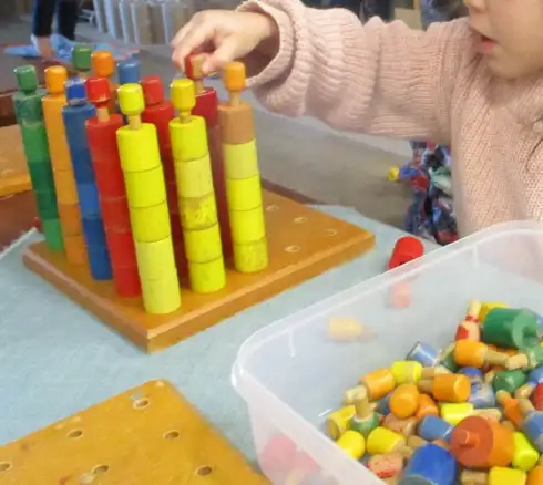 A child stacking coloured wooden pegs onto a peg board at Children's Ark