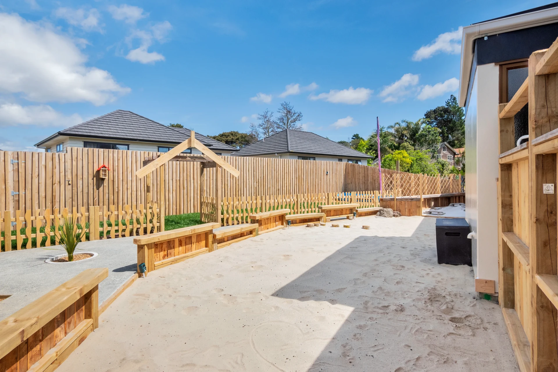 The big sandpit with timber benches and a shaded corner